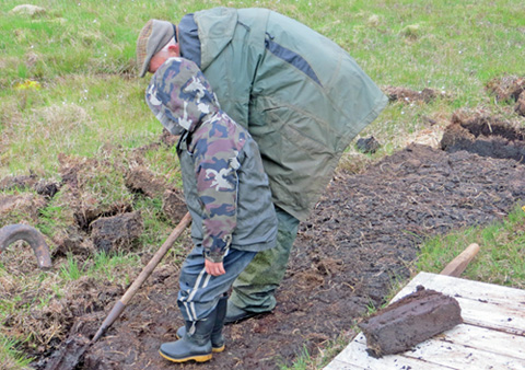 The children from Ulva School learnt about cutting peat. Photo of school-child trying peat cutting